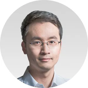 Portrait of a man wearing glasses and a light blue shirt, with a neutral expression and short hair.