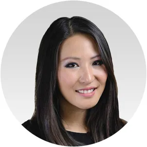 Portrait of a smiling woman with long black hair against a light gray circular background.